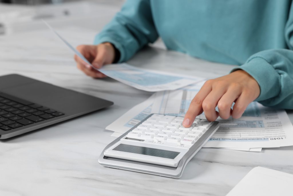 Woman calculating taxes at white table, closeup