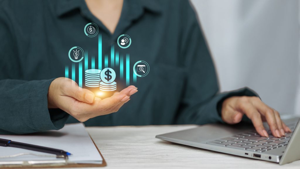 Businesswoman using laptop with digital money and financial growth icons in hand, online investment, banking, fintech technology concept.